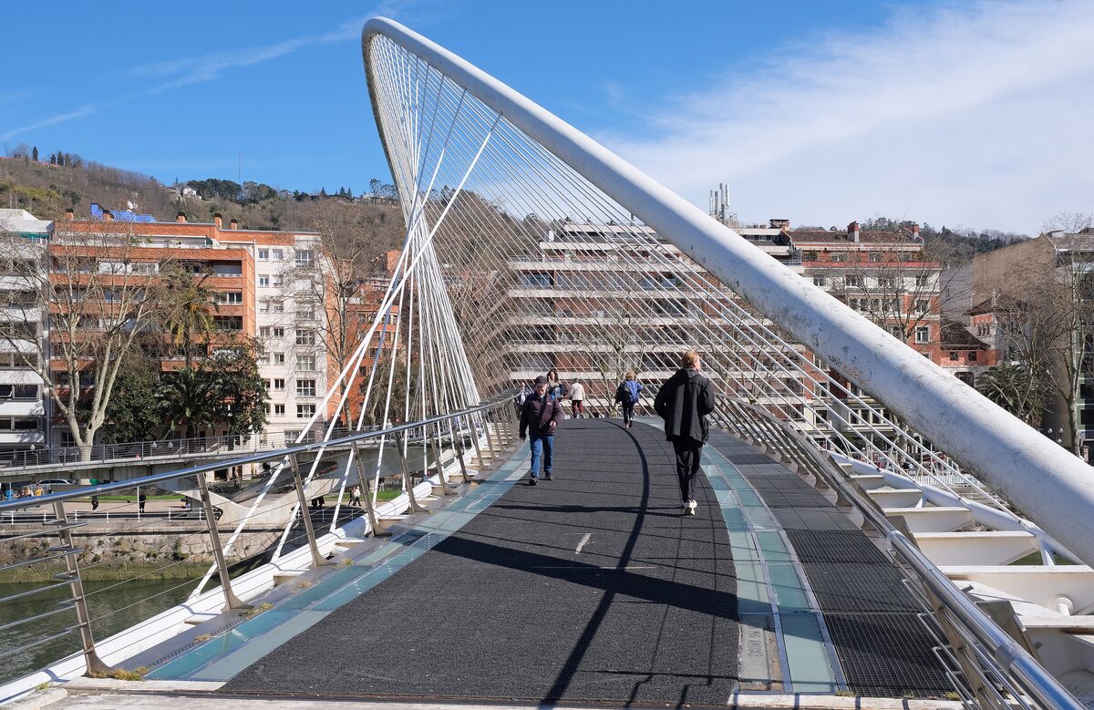 The white arched Zubizuri footbridge over the Nervión, with people walking across the deck