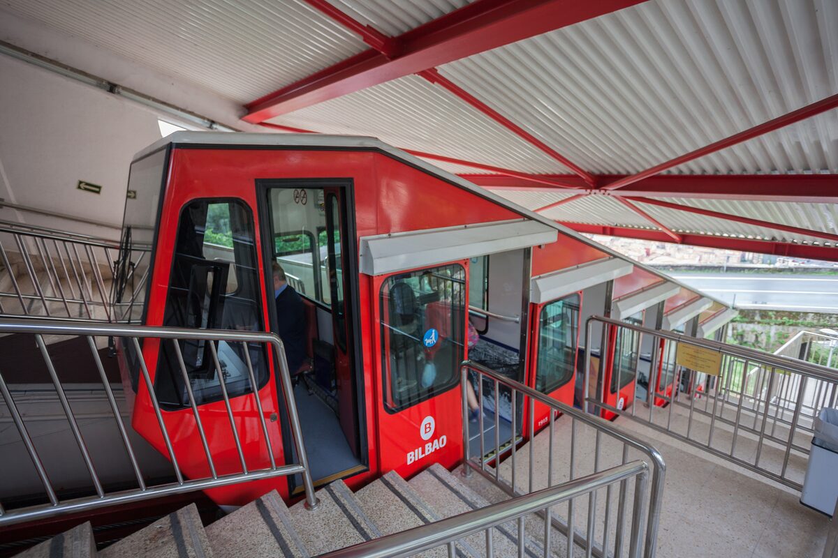 A red Artxanda funicular car at its station, with the steps and railings beside it