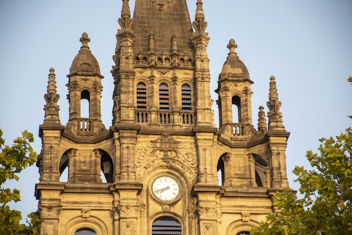 The clock tower and spire of the Basilica of Begoña against a clear sky
