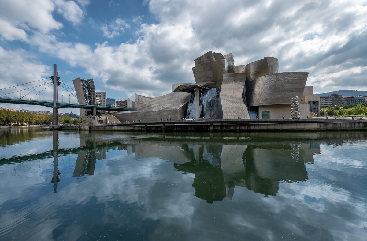 The Guggenheim with its titanium curves reflected in the Nervión, and a footbridge on the left