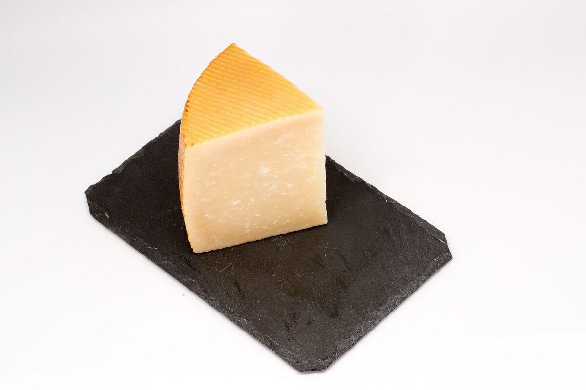 A wedge of smoked Idiazabal cheese on a dark slate board