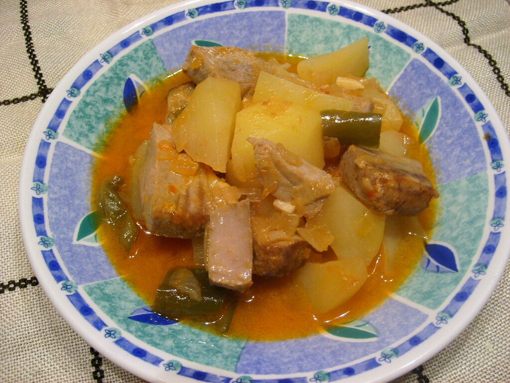 A bowl of marmitako, the tuna and potato stew, with green pepper in an orange broth
