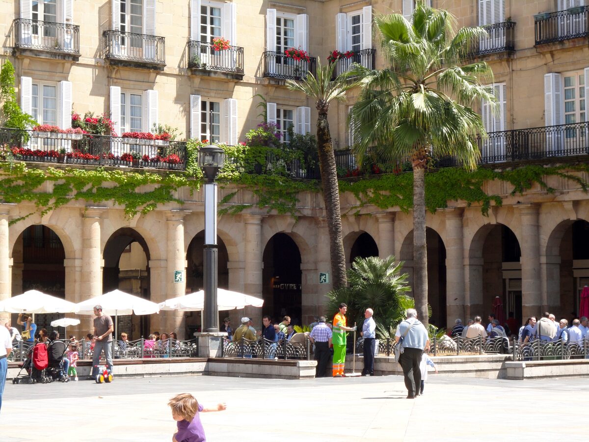 The arcaded Plaza Nueva with palm trees and café tables under the arches