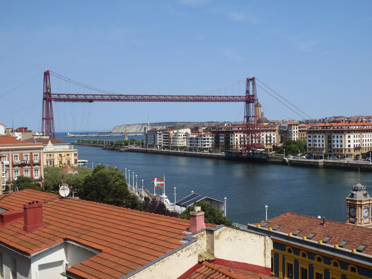 Red tile roofs of Portugalete above the Nervión, with the Vizcaya Bridge crossing the estuary