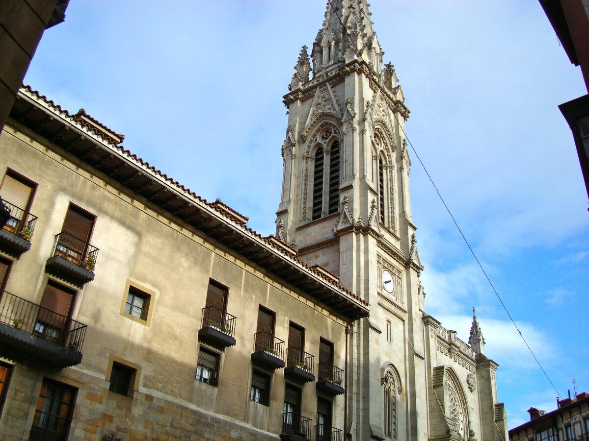 The openwork stone tower and spire of the Santiago Cathedral rising above old balconied houses in the Casco Viejo