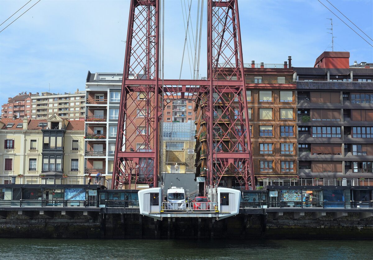The red steel towers of the Vizcaya Bridge, with the transporter gondola at the riverbank below