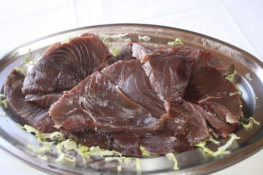 A metal platter of raw sliced bluefin tuna on shredded lettuce