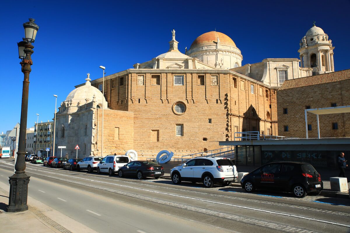 Cádiz Cathedral from the southeast, its dome above a street of parked cars