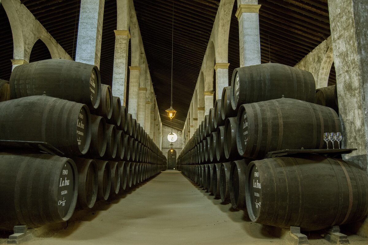 Rows of sherry butts lining an arched cellar, with a lamp hanging in the middle