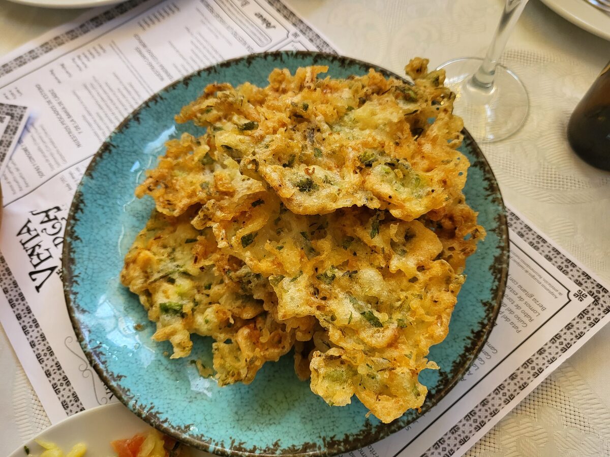 Golden tortillitas de camarones piled on a turquoise plate