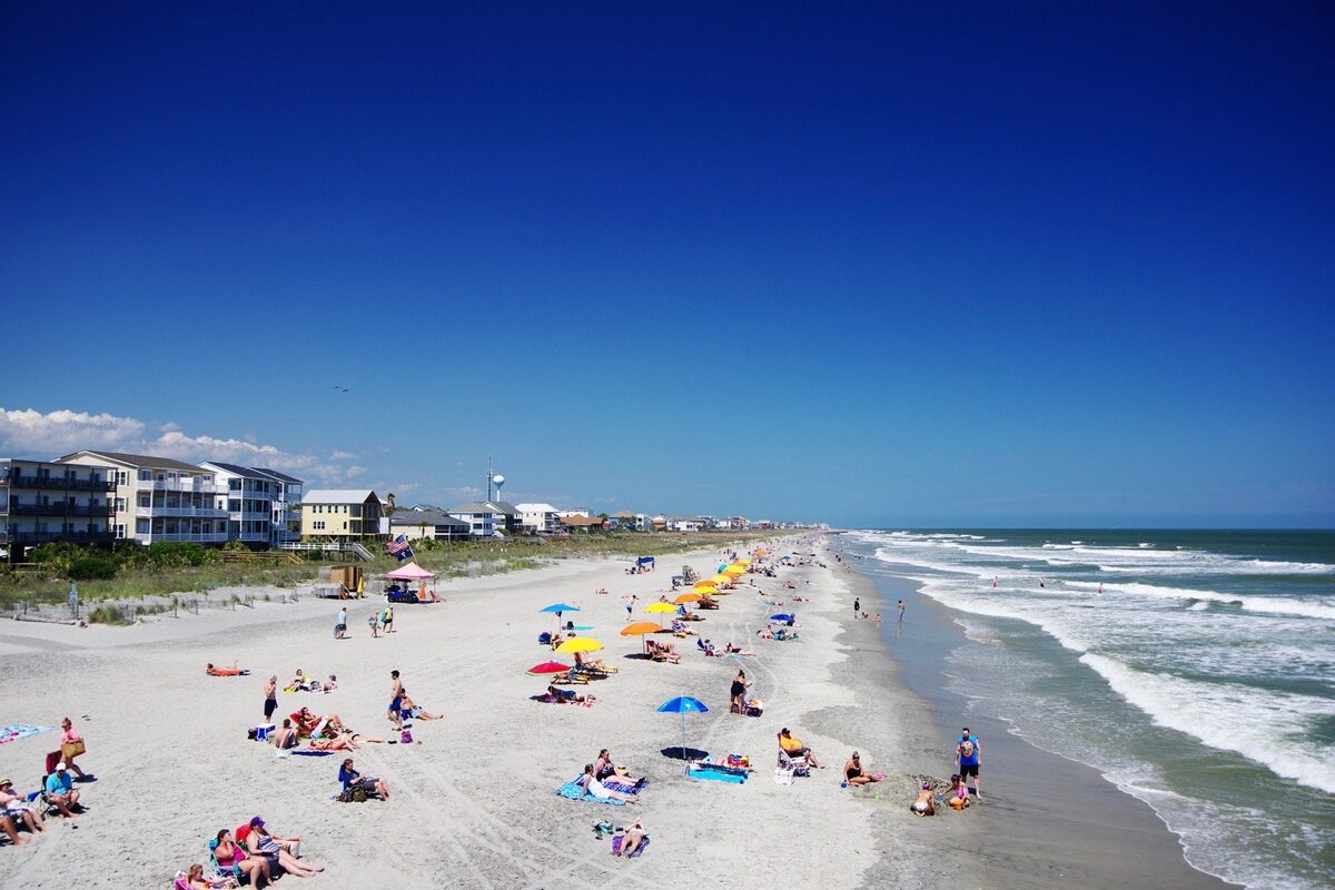 Sunbathers and colorful umbrellas on the wide sand of Folly Beach