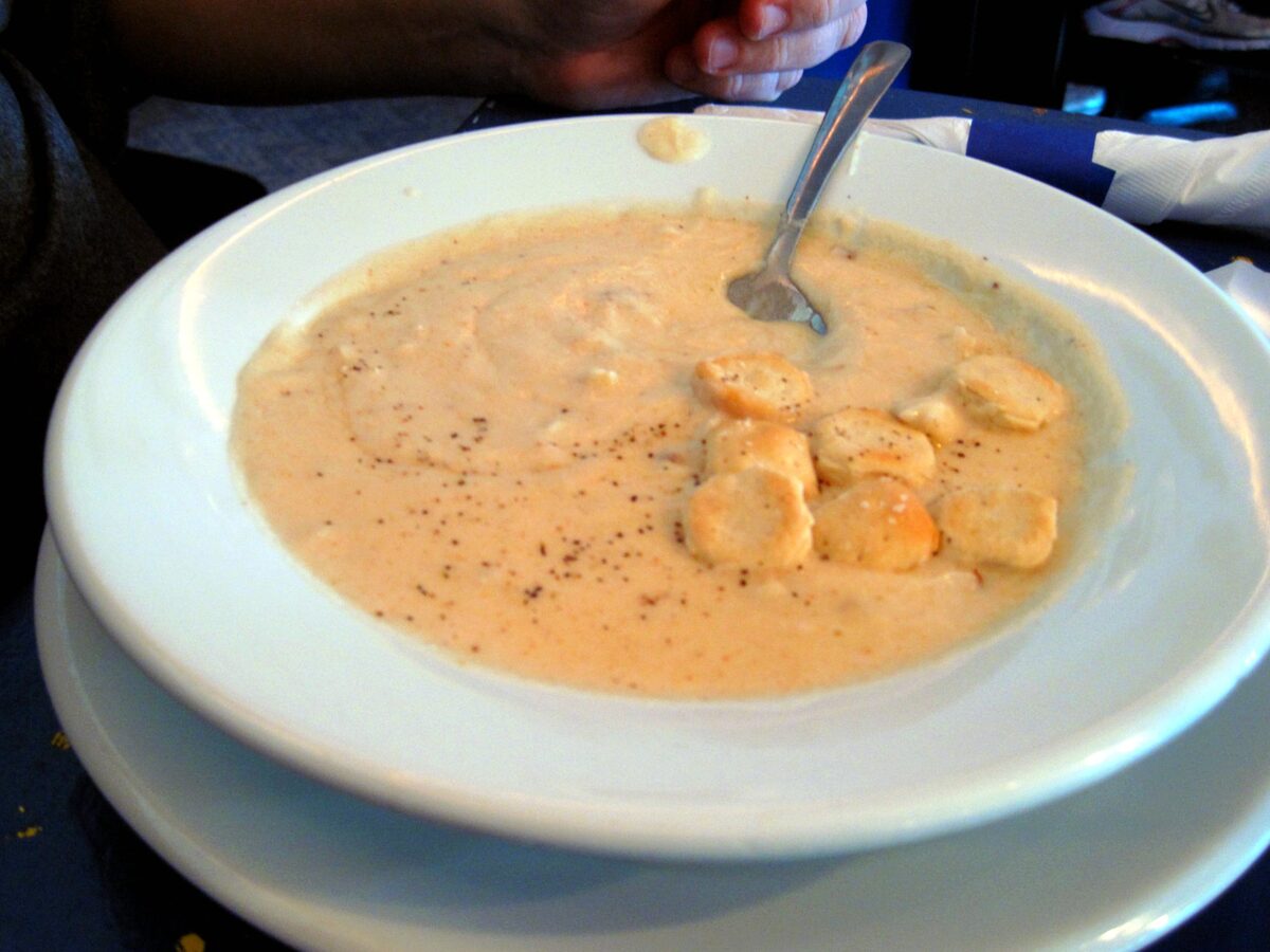 Bowl of creamy orange she-crab soup with oyster crackers on top