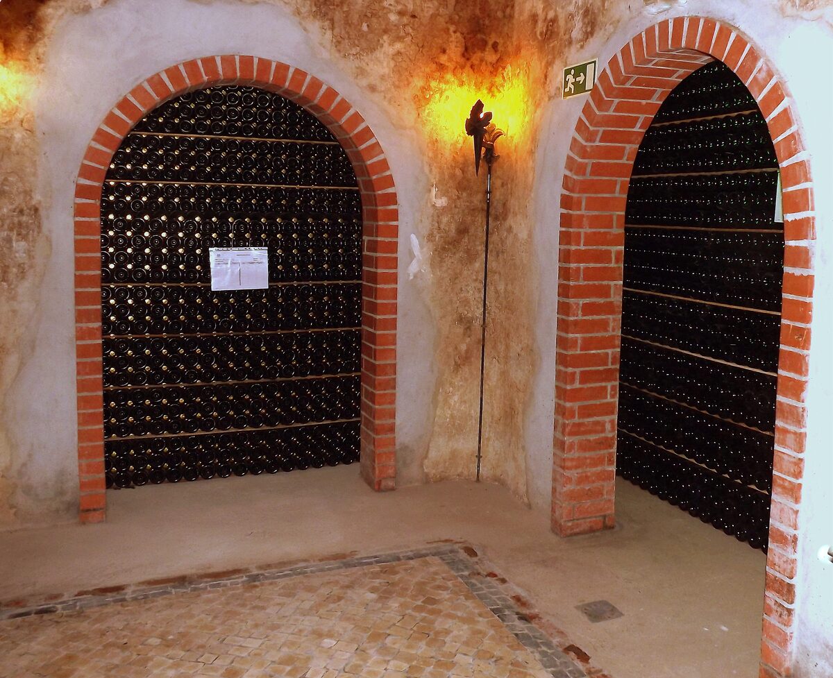 Two brick-arched cellar bays packed with rows of sparkling wine bottles ageing in the cooperative cellars of Cantanhede, in the Bairrada region