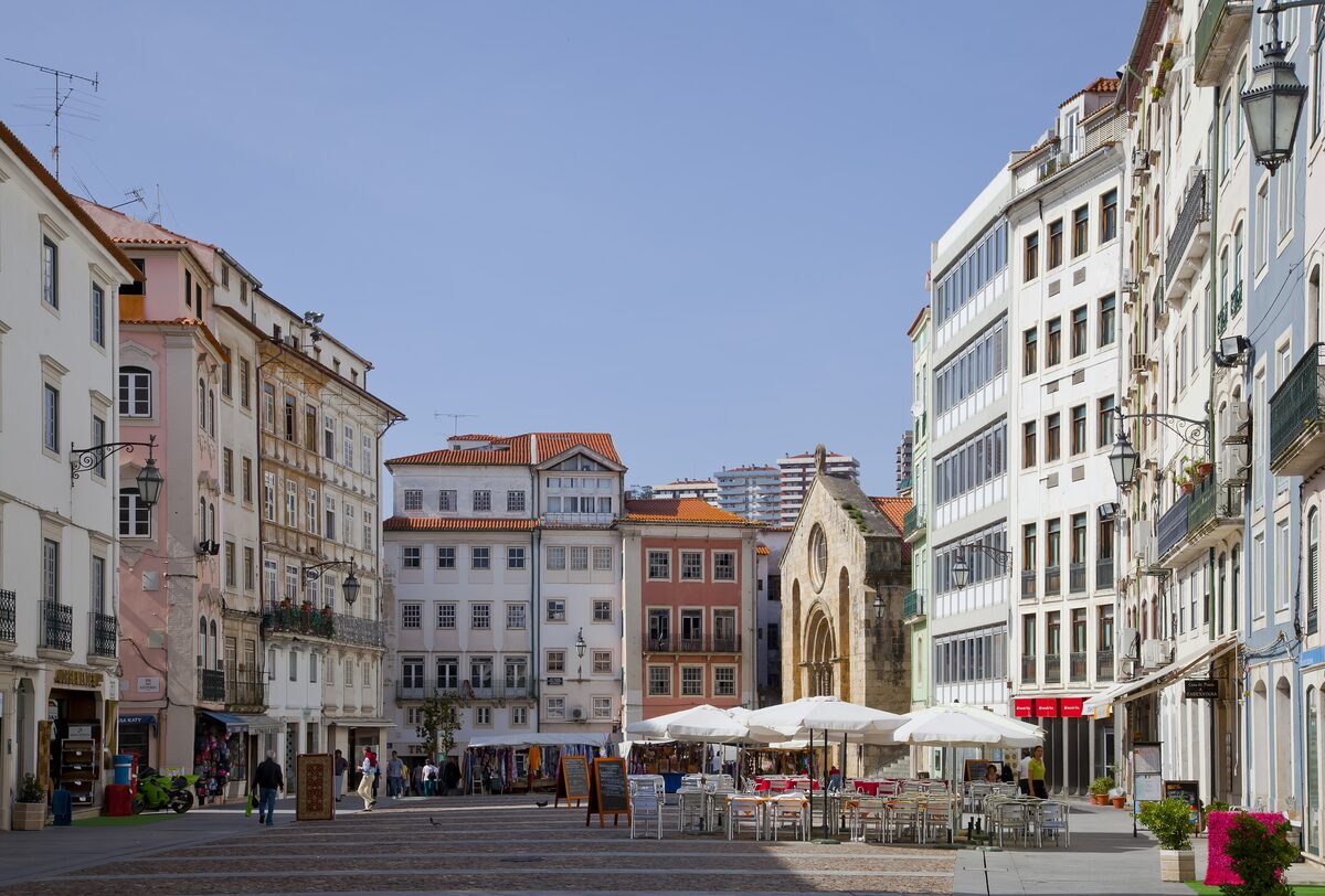 Praça do Comércio in the Baixa, the lower town, with cafe terraces under white umbrellas in front of tall pale buildings