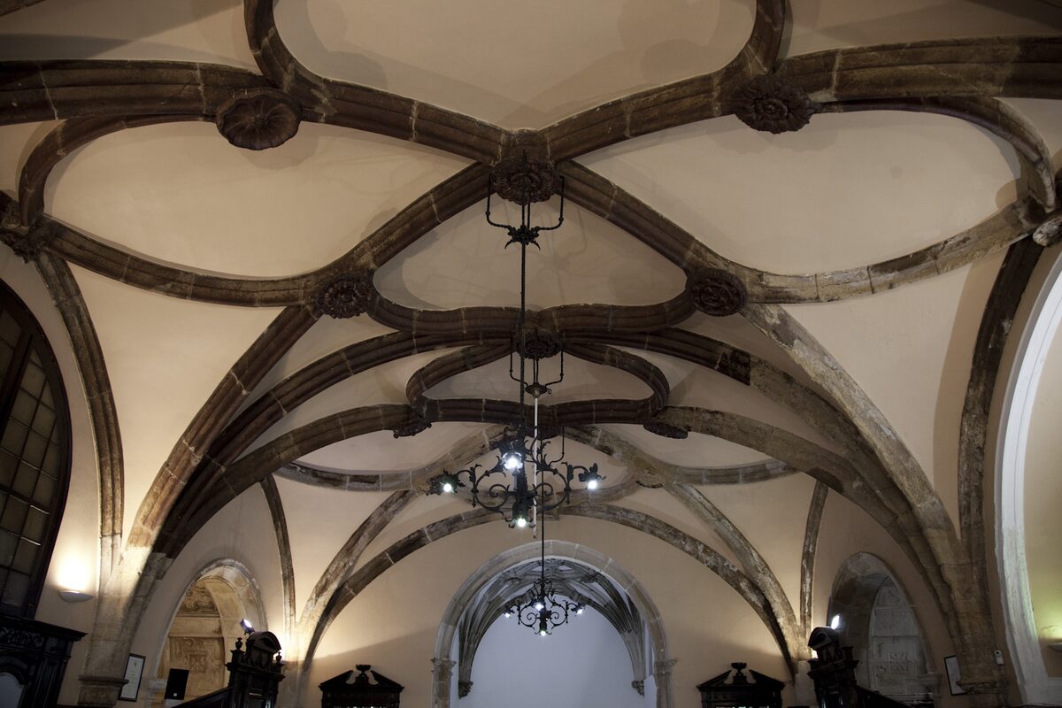 The ribbed stone vault of the former church of São João de Santa Cruz, now a cafe, with a chandelier hanging from the star-patterned ceiling