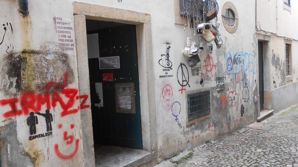 The doorway of a student republic on a narrow street, its walls covered in graffiti and posters