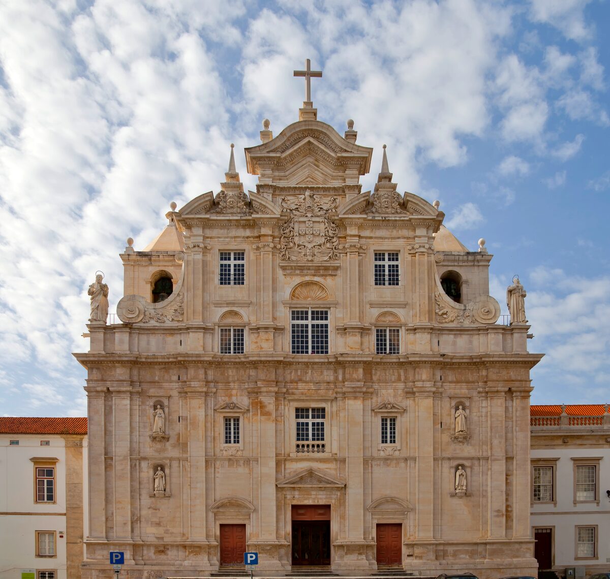The pale baroque facade of the New Cathedral, the Sé Nova, with its central doorway and a cross above the pediment