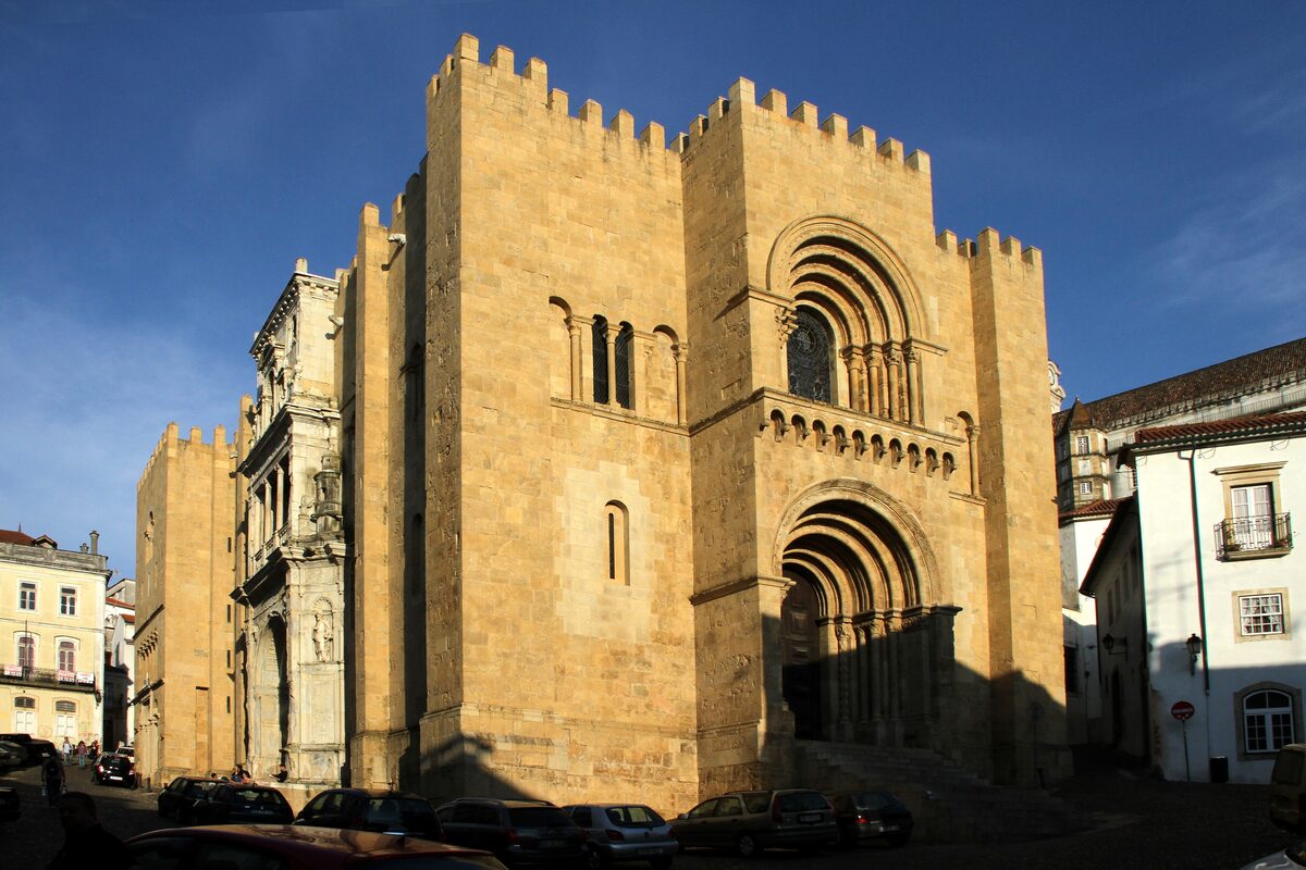 The crenellated Romanesque facade of the Old Cathedral, Sé Velha, with its round-arched doorway and square tower