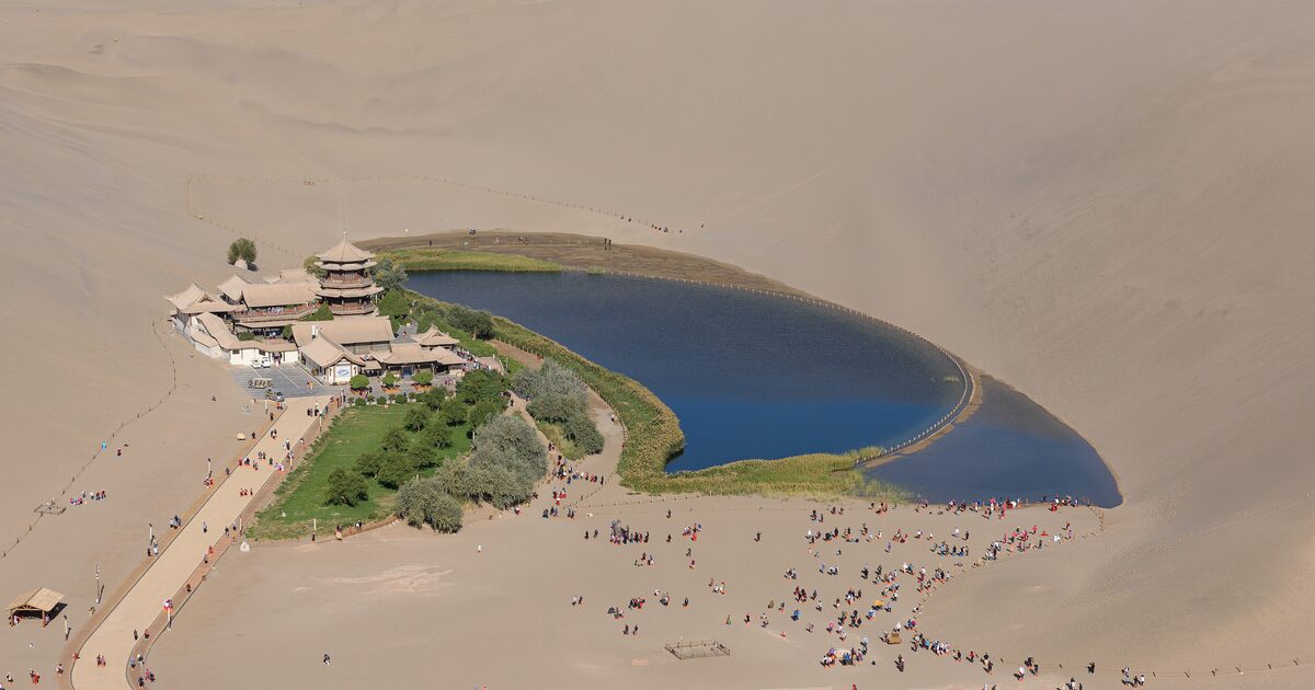 Aerial view of Crescent Lake in a hollow between the sand dunes of Mingsha Shan, with the pagoda-roofed pavilions on the shore