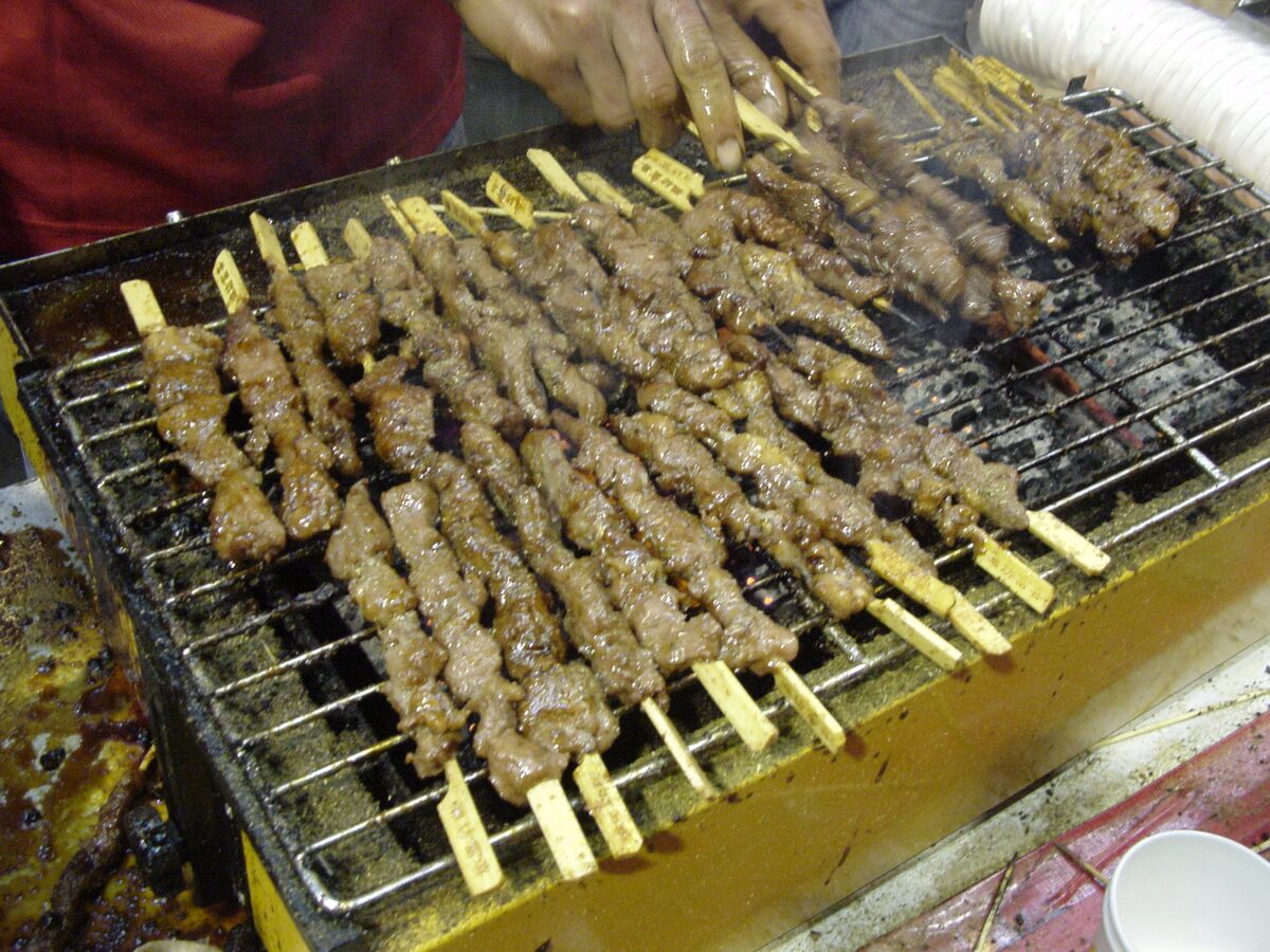 Rows of barbecued lamb skewers on a grill at a street stall in China