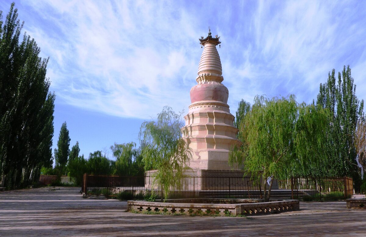 The tiered white-and-pink White Horse Pagoda among poplar and willow trees under a blue sky