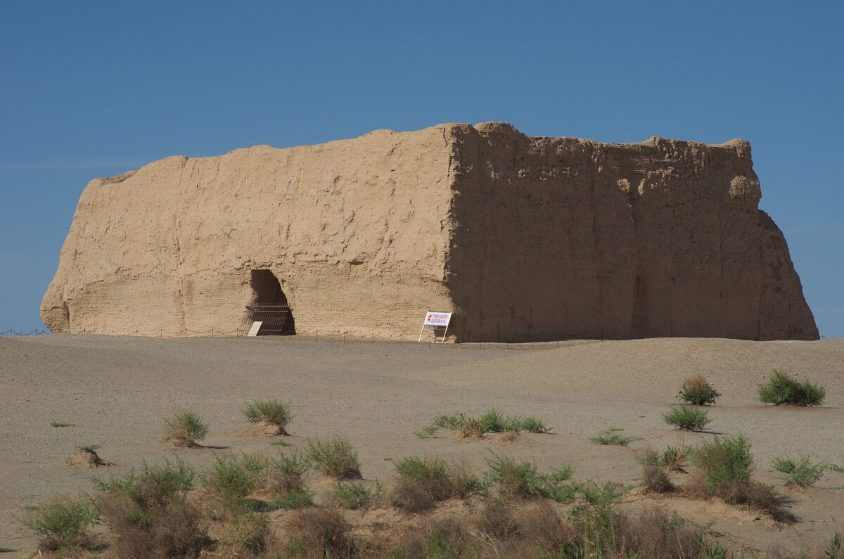 The rammed-earth walls of the Yumen Pass fort standing alone in the Gobi under a blue sky