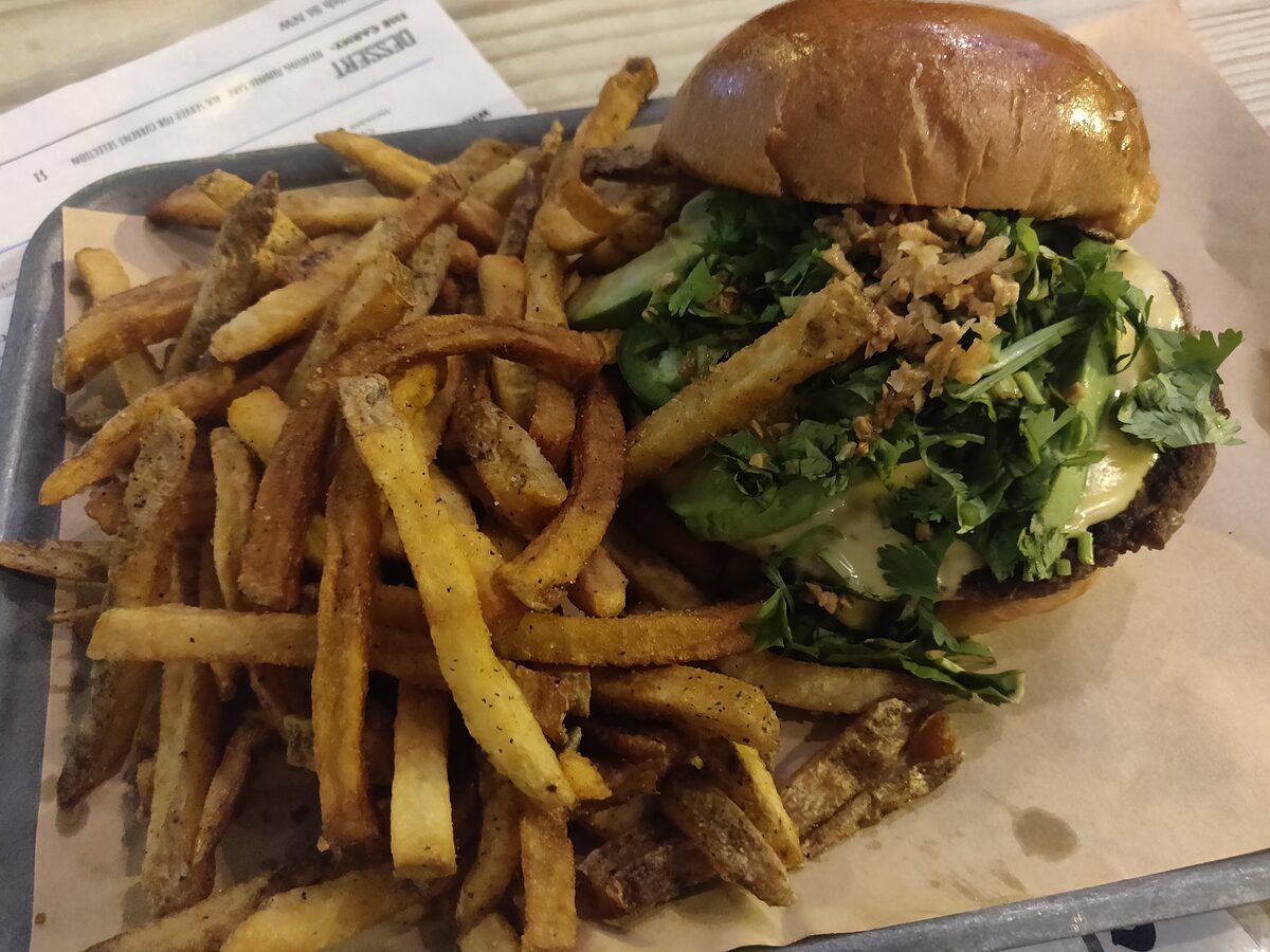 A burger with greens and a tray of hand-cut fries