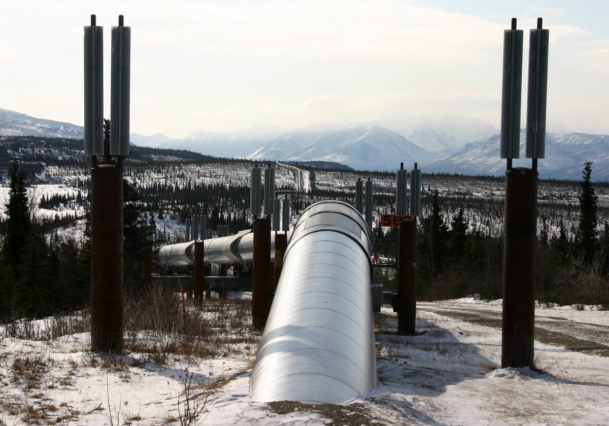 The Trans-Alaska Pipeline on rust-brown supports in snow, with mountains behind