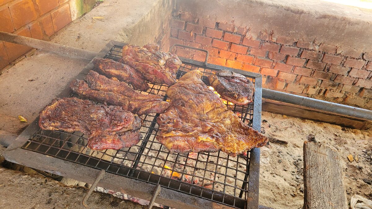 Beef ribs and cuts cooking over wood coals on a brick grill, the Argentine parrilla way