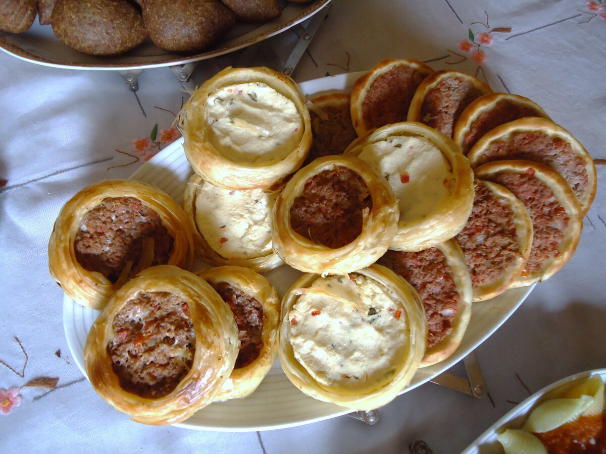 A plate of small baked esfihas topped with spiced minced beef and white cheese