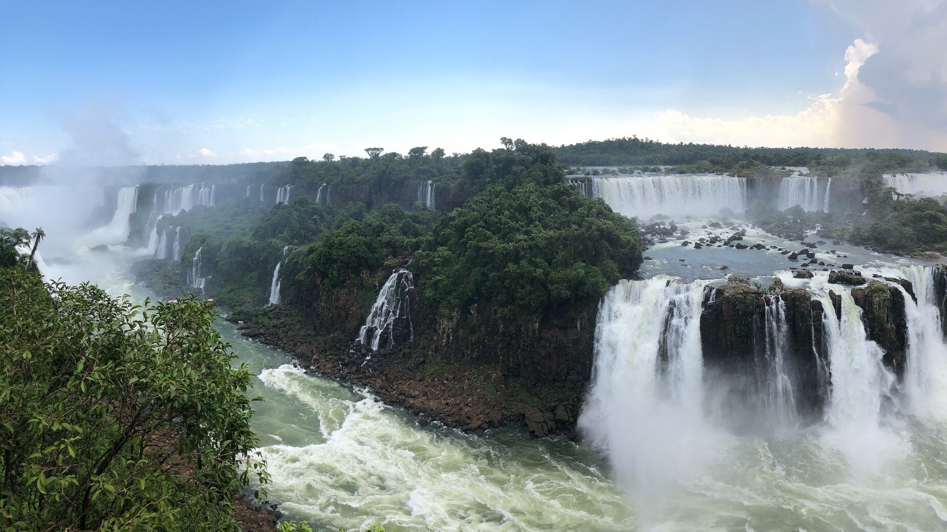 Iguazu Falls from the Brazilian side under a blue sky, a wide panorama of the cascades