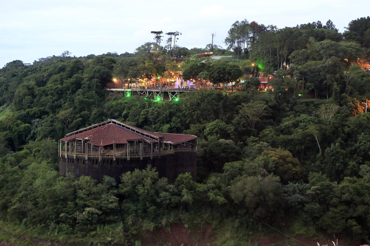 The Marco das Três Fronteiras complex on its wooded hill, its restaurant building lit up in the evening
