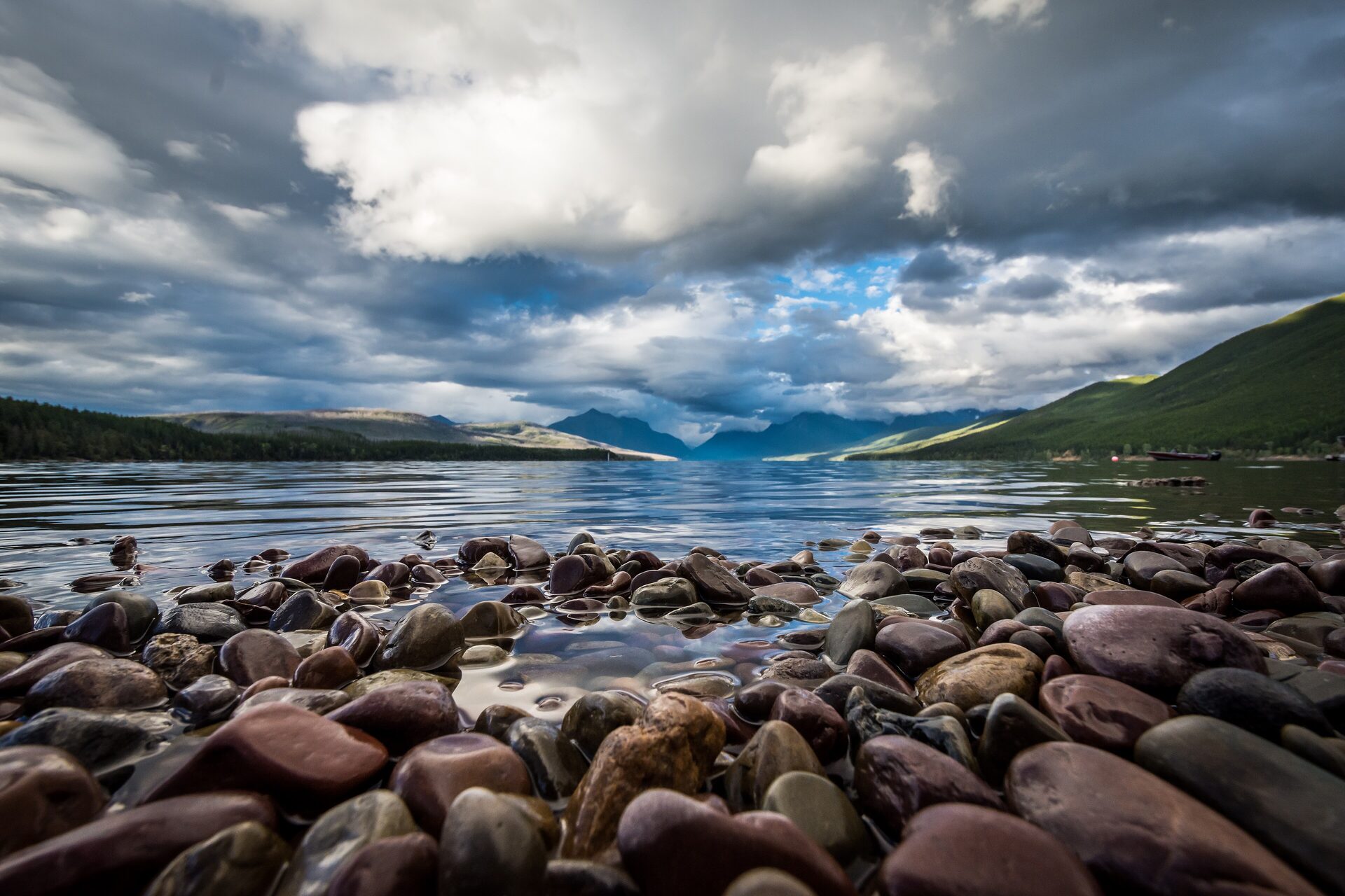 Colorful stones on the Lake McDonald shore beneath cloudy mountains