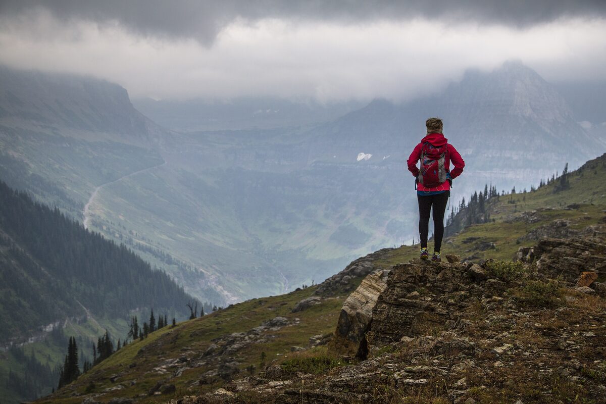 A hiker on a rocky ledge above the valley on the Highline Trail