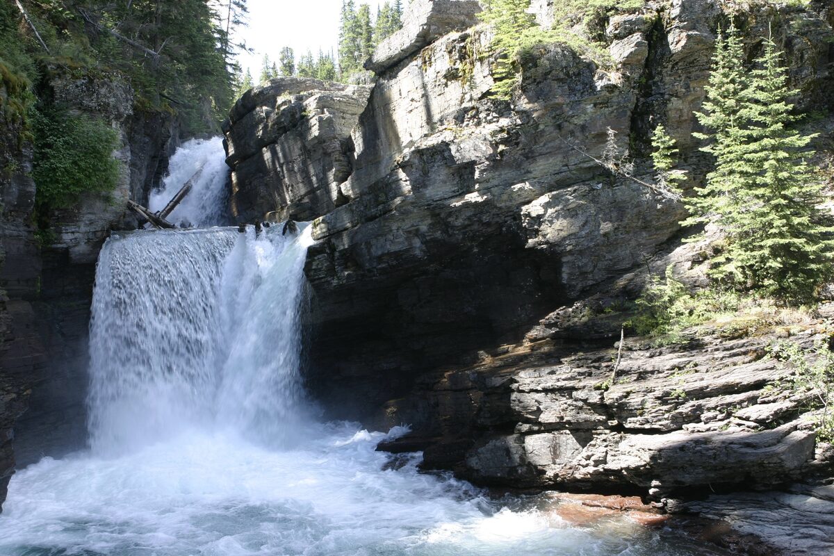 St. Mary Falls plunging over rocks into a green pool