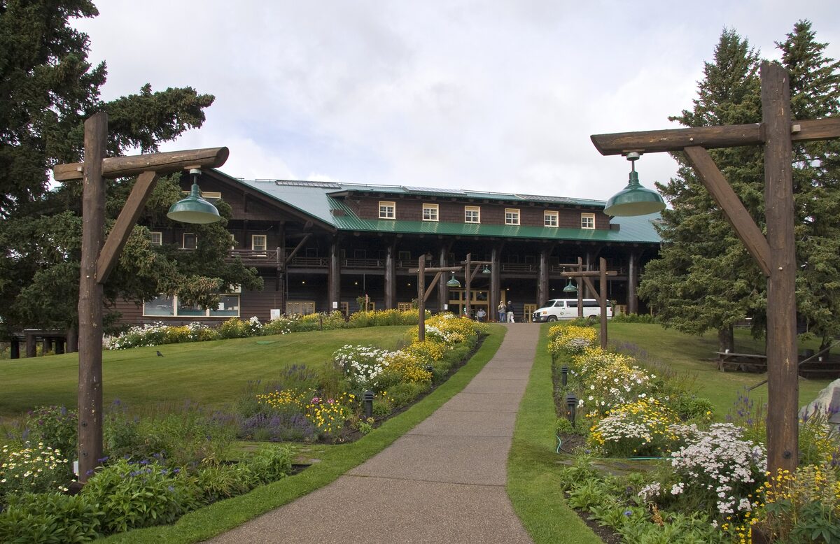 Glacier Park Lodge behind a flower-lined path and log gates