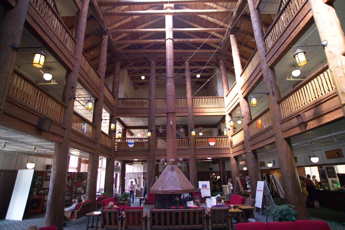 Timber lobby of Many Glacier Hotel with a central fireplace