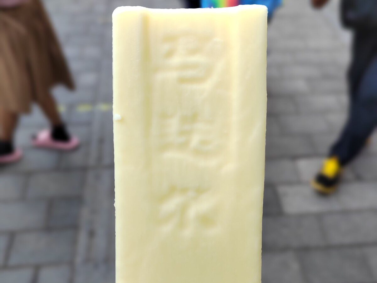 A pale cream Madieer ice lolly held up, with the brand name pressed into the ice cream