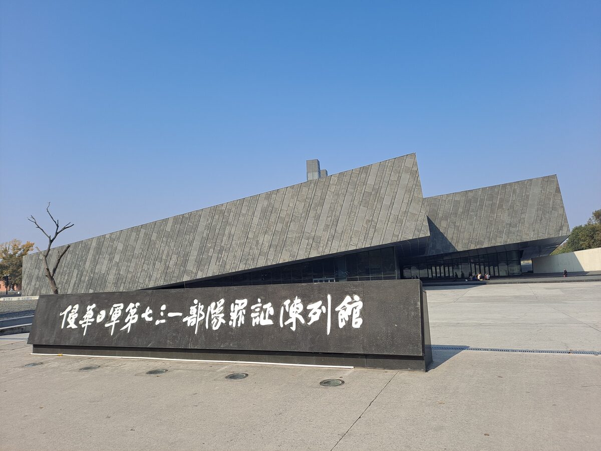 The low gray exterior of the Unit 731 exhibition hall with its name carved on a stone wall in front
