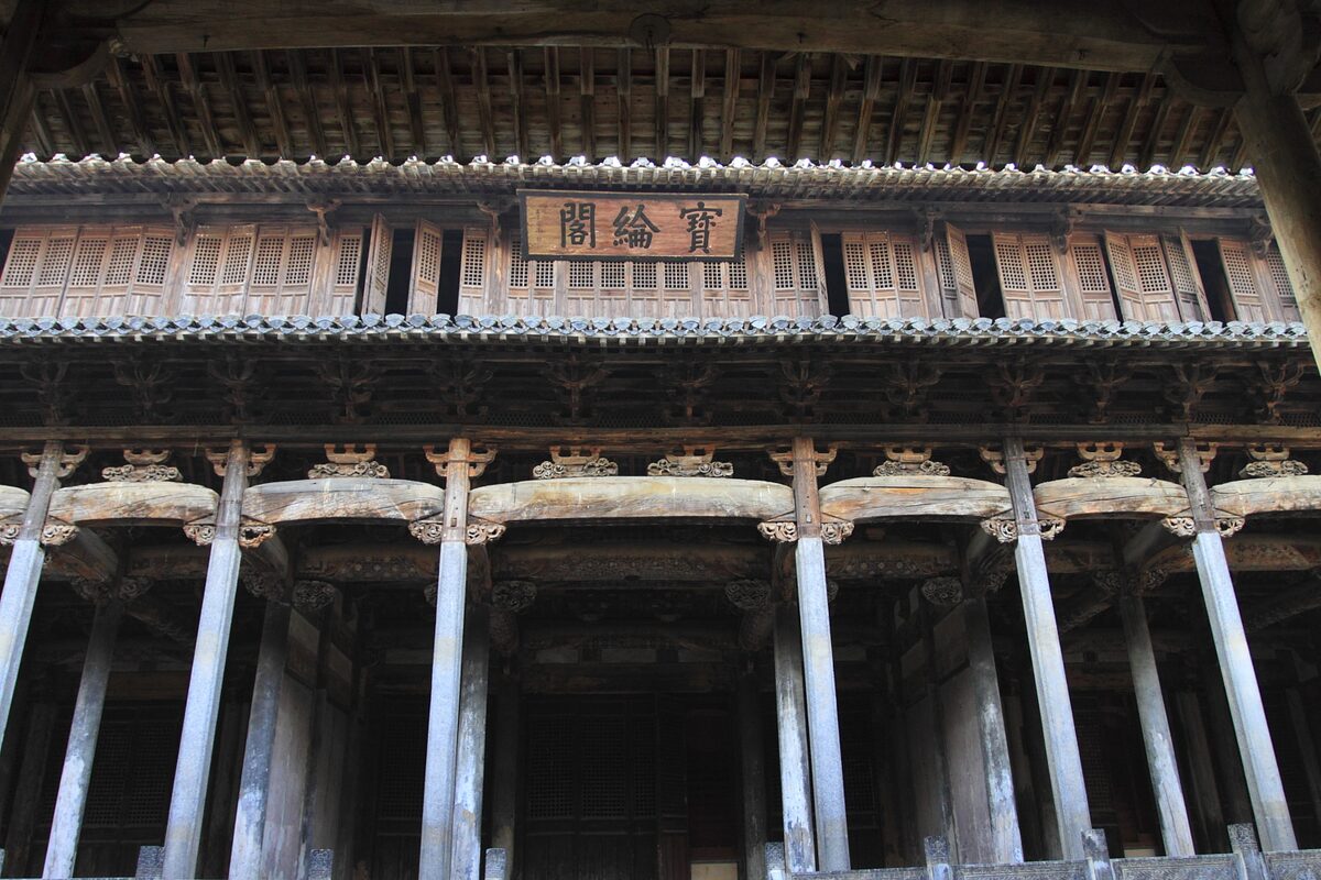 The carved two-story wooden Baolun Pavilion on tall stone-gray columns in Chengkan's Luo Dongshu ancestral hall