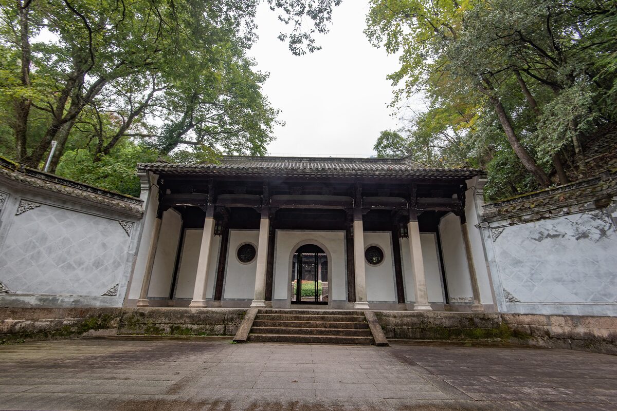 The white-walled front hall of Ciguang Pavilion, with a stone forecourt and trees overhead