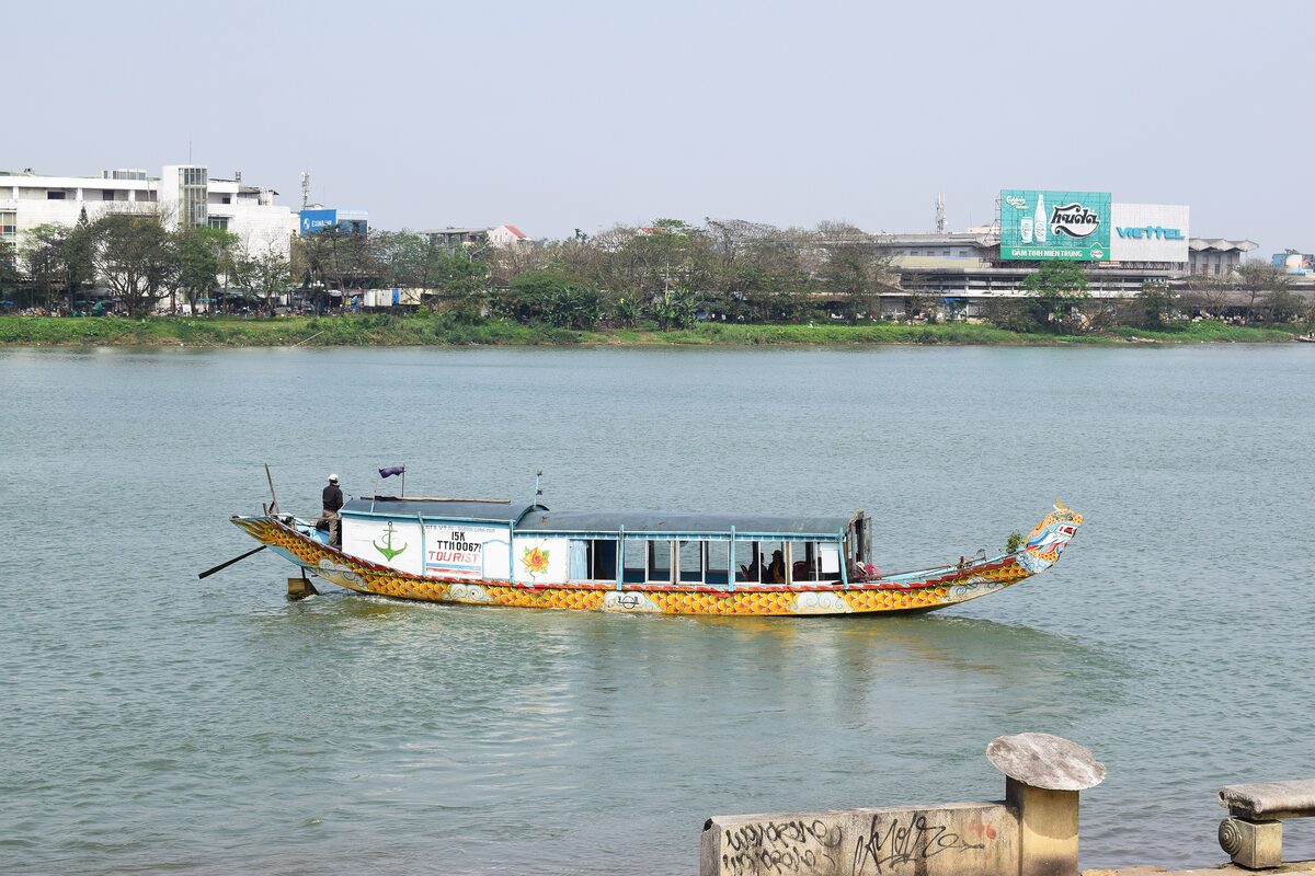 A painted wooden dragon boat with a covered deck on the Perfume River