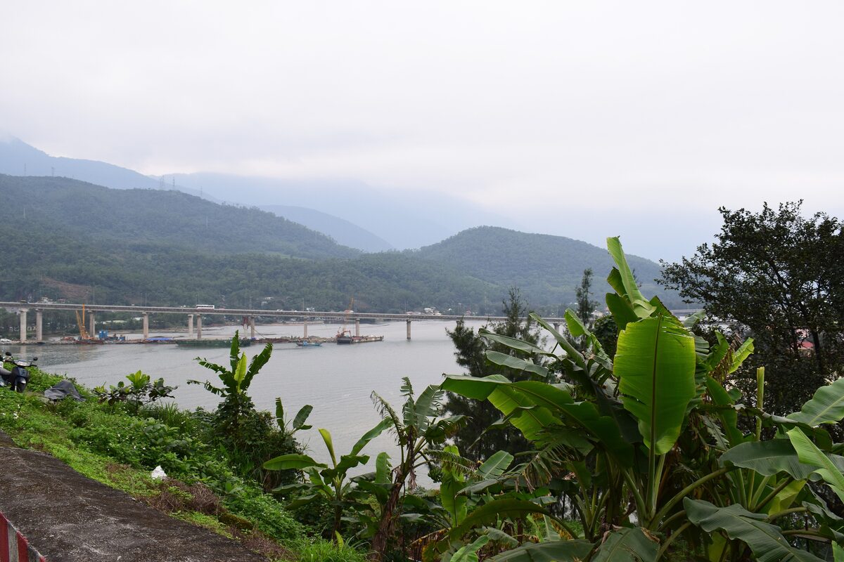 The Lang Co lagoon with a long bridge across the water and green mountains behind