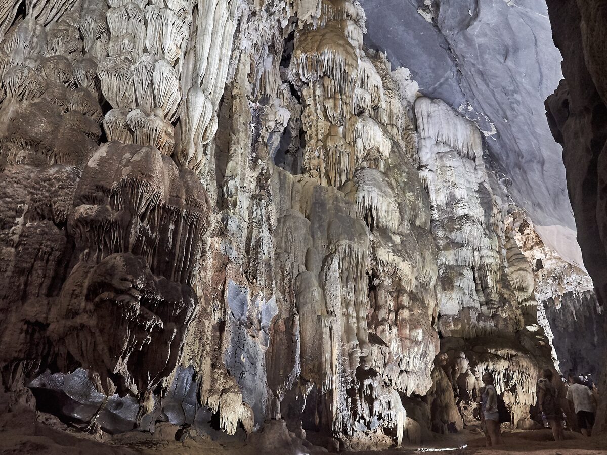 Stalactites and rock formations inside Phong Nha Cave, with visitors at the bottom