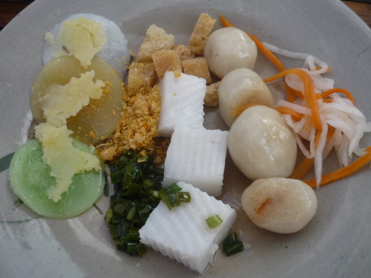 A plate of small Hue steamed cakes with scallion oil, crispy toppings and pickled carrot