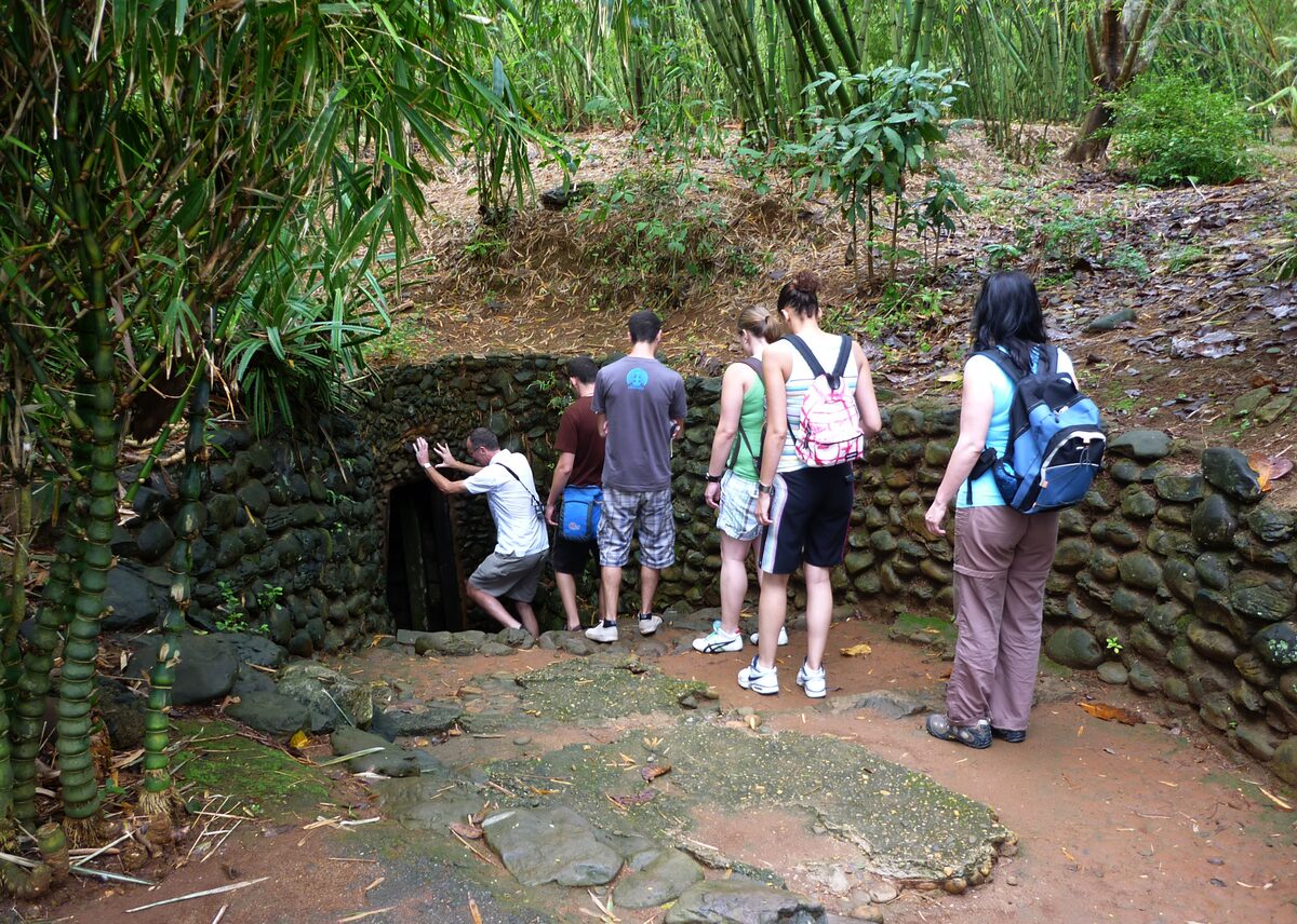 Visitors at the stone-walled entrance to the Vinh Moc tunnels, half hidden in bamboo
