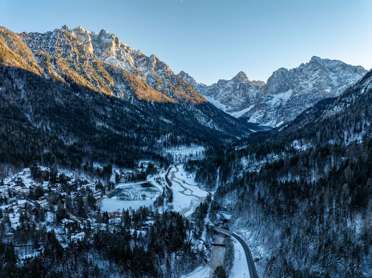 Kranjska Gora from the air in winter, the village and the Sava Dolinka valley below snow-dusted Julian Alps in low sun