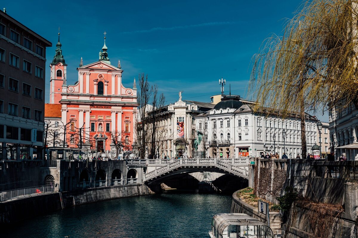 The pink Franciscan Church and the Triple Bridge over the Ljubljanica river in the old town of Ljubljana