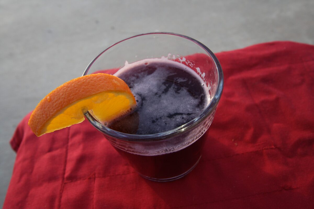 A glass of hot mulled red wine with an orange slice on its rim, standing on a red cloth