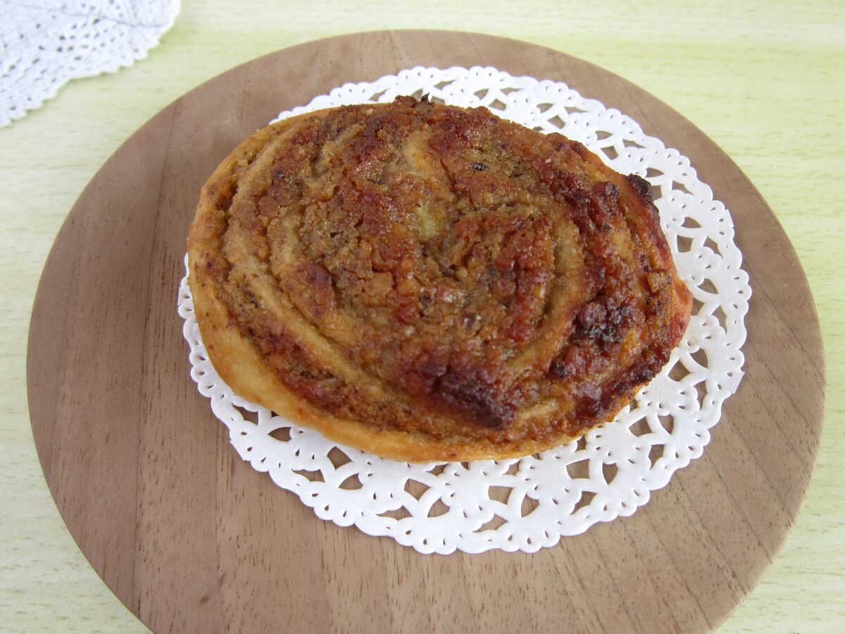A round slice of potica, a rolled nut pastry, on a wooden board with a paper doily